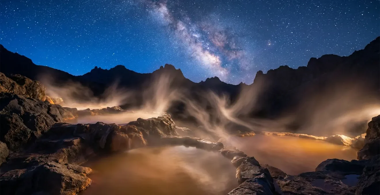 Sources chaudes naturelles sous un ciel étoilé avec vapeur d'eau s'élevant dans la nuit