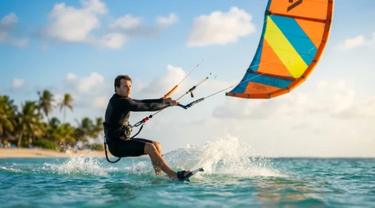 Kitesurfeur débutant en position de waterstart dans une lagune aux eaux cristallines, aile colorée tendue dans le ciel azur